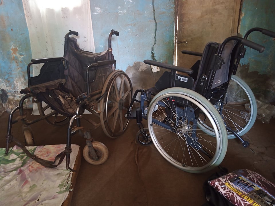 A ruined wheelchair next to a new wheelchair.